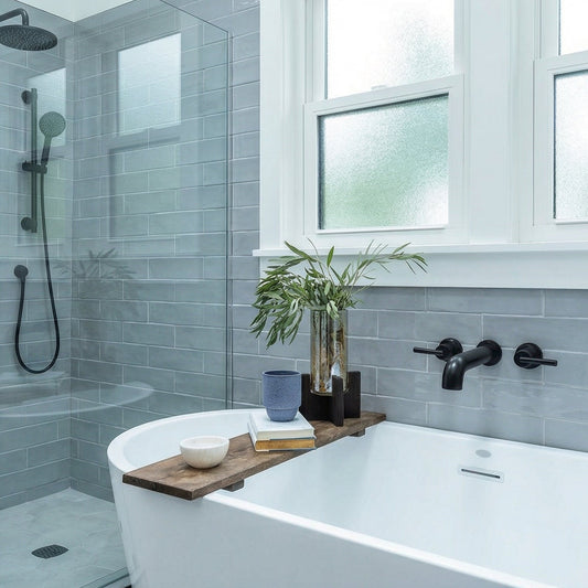 A modern bathroom featuring a white freestanding bathtub with a wooden tray table, a glass walk-in shower enclosure, and light gray subway tile walls under frosted windows.
