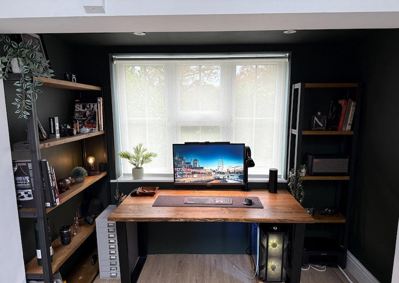 Home office with a wooden desk flanked by two tall shelving units with black metal frames
