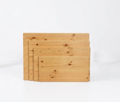Four rectangular light tan wooden boards in a cascading stack with visible knots
