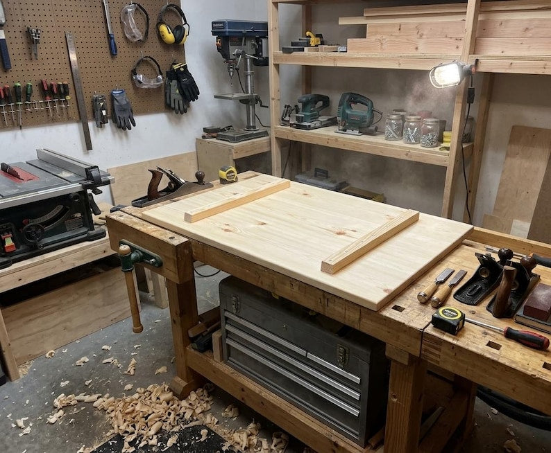 Large light wooden board with two battens attached underneath on a workbench