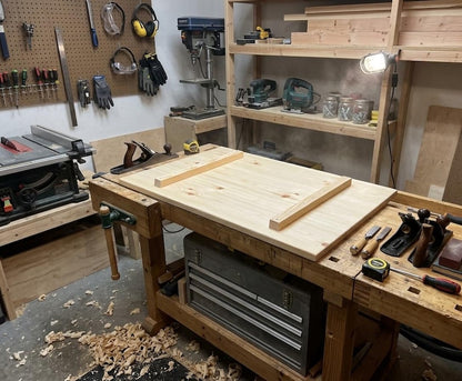 Large light wooden board with two battens attached underneath on a workbench