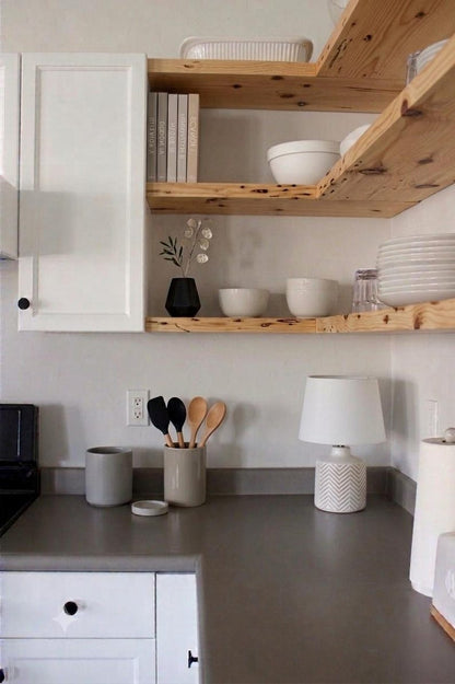 Natural wood floating shelves in a kitchen with white cabinets