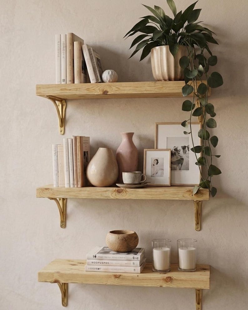 Three light wooden shelves with gold-coloured brackets