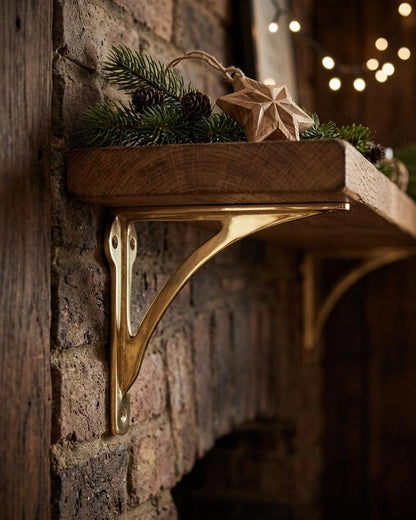 Polished brass shelf bracket supporting a thick wood shelf