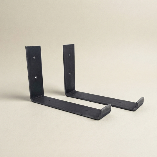 Two black metal L-bracket wall mounts shown on a plain beige studio background.
